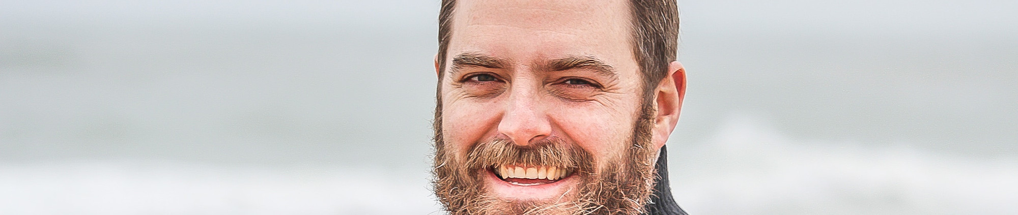 Smiling man with beard at the beach.